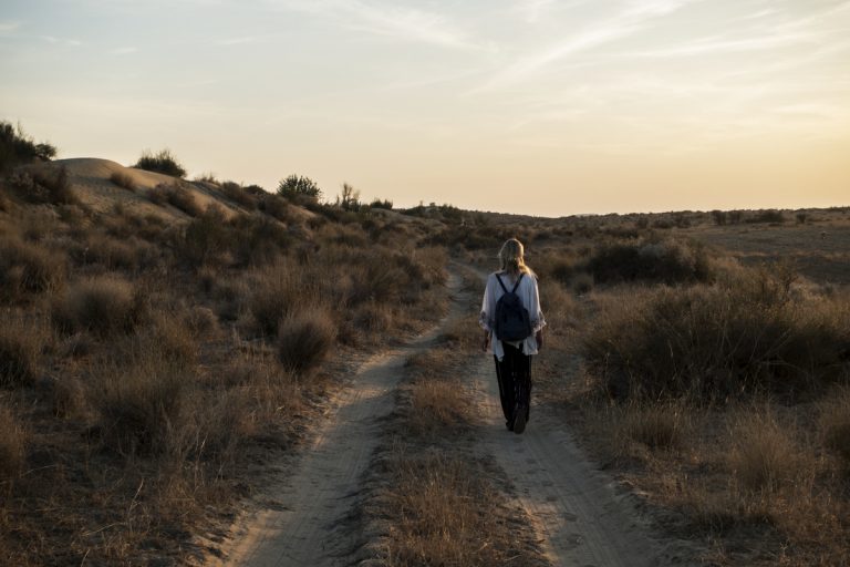 אישה מטיילת על שביל כפרי לבד בשקיעה